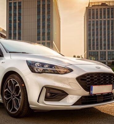 Ford sedan with Bolt logo on door against a cityscape backdrop