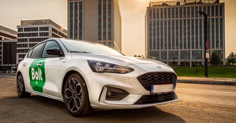 Ford sedan with Bolt logo on door against a cityscape backdrop