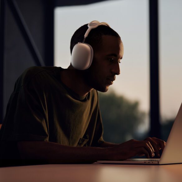 Man waering AirPods Max while working on his MacBook