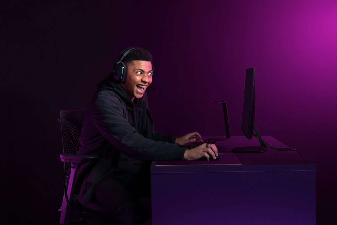 excited person sitting in front of a computer against a purple background