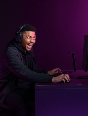 excited person sitting in front of a computer against a purple background