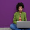 generic image of a woman sitting on the floor while busy on her laptop