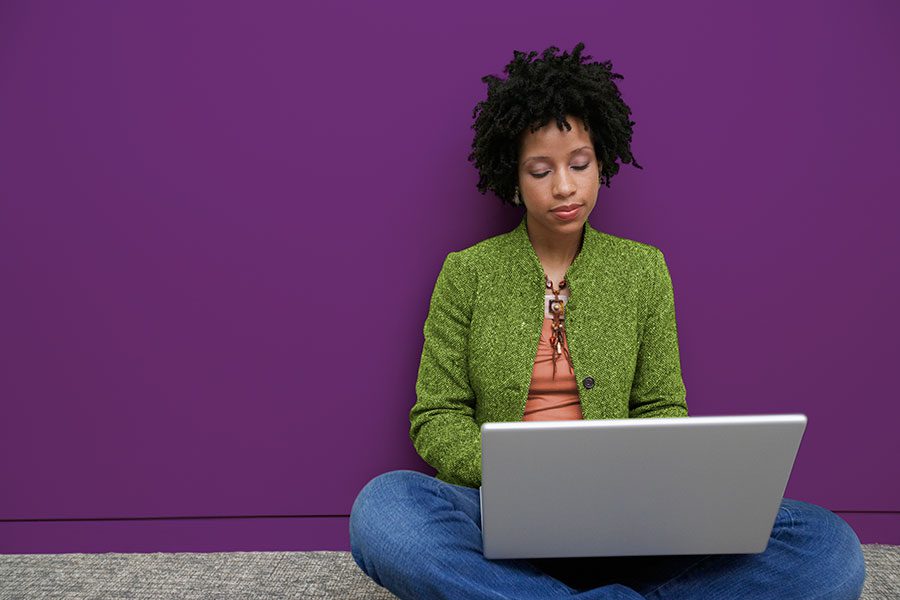 generic image of a woman sitting on the floor while busy on her laptop