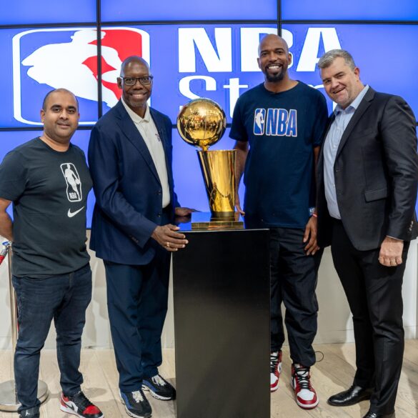 Group image of NBA Africa CEO Victor Williams, Shesha CEO Nirmal Devchand and 2004 NBA champion Richard “Rip” Hamilton in front of an NBA sign with an NBA trophy at the opening of the first NBA store in Africa