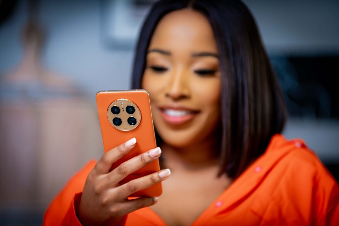 Picture of a woman wearing orange holding an orange HUAWEI Mate50 Pro